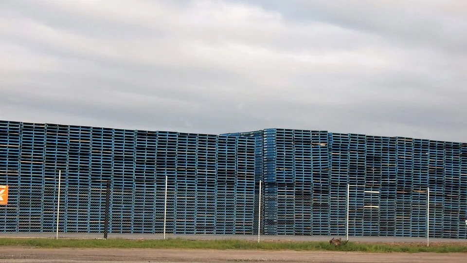 Stacks of plastic pallets stored outdoors at a distribution yard